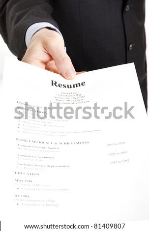 Closeup of a businessman\'s hand holding out a resume.  Focus on the hand and the word Resume.