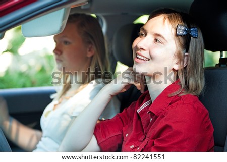 Teen girl is distracted, fixing her hair in the mirror, while driving the car.