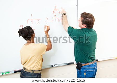 High school student and teacher at the white board doing long division.  Focus on the equations.