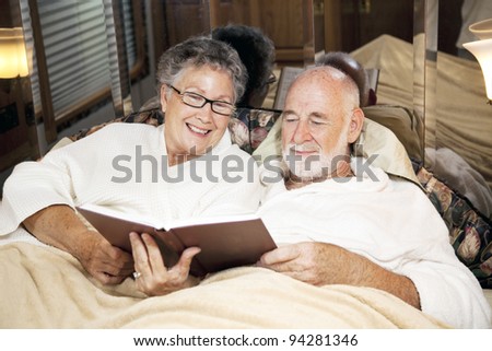 Senior couple reads together at bedtime, in their motor home.