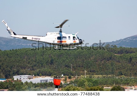 POMBAL, PORTUGAL - JULY 25 : Fire rescue heavy helicopter, with water bucket, droping water on a fire in Pombal July 25, 2010 in Pombal, Portugal