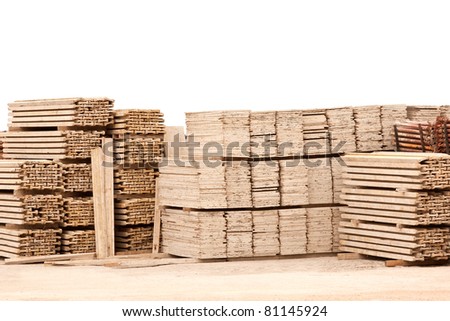 Pile of wooden planks in gravel ground against white wall