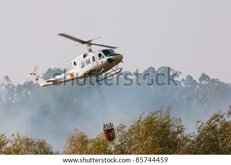 POMBAL, PORTUGAL - OCTOBER 1 : Fire rescue heavy helicopter, with water bucket, prepares f to scoop water in order to combat a fire in Pombal on October 1, 2011 in Pombal, Portugal.