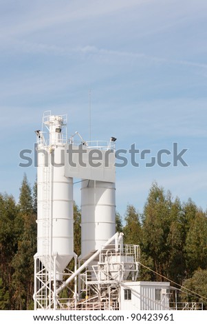 processing silos of a concrete factory against forest and blue sky