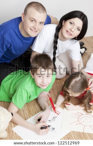 Portrait of a beautiful family: parents and children play together and draw