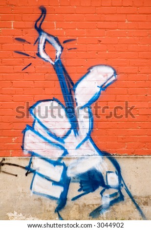 Brightly colored graffiti hand on a orange brick wall.