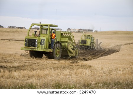 Motor Scrapers tearing up a farmers field for a new subdivision.