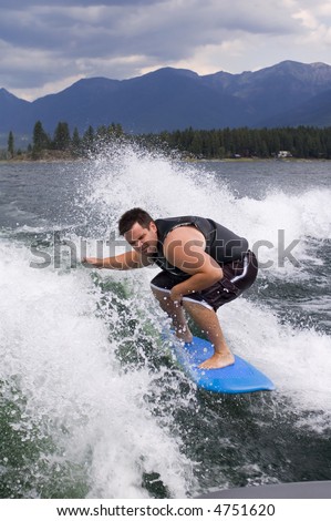 Man skurfing on the wake of a boat.