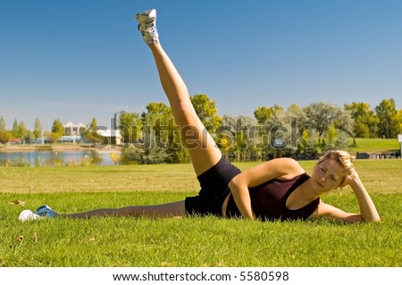 Young woman doing leg lifts in a park.