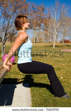 Young woman performing tricep dips on a bench.