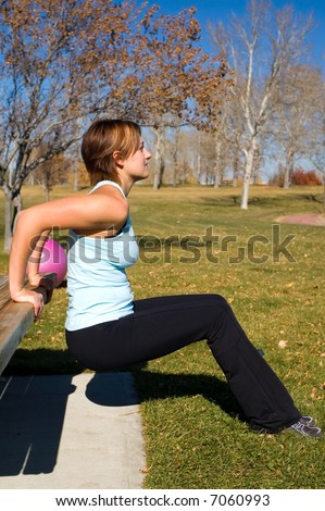 Young woman performing tricep dips on a bench.