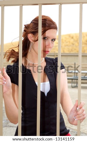Attractive young woman trapped behind bars.