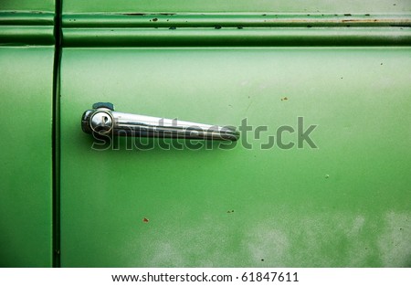 Car door handle on a green door.
