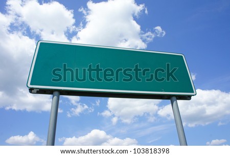 Empty green road sign against blue sky with clouds - a place for your own text on a green sign.