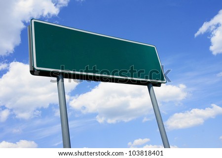 Empty green road sign against blue sky with clouds - a place for your own text on a green sign.
