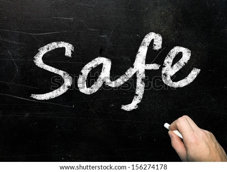 The word Safe handwritten in white chalk on a used blackboard