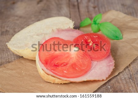 A piece of ham and tomato on old wooden counter