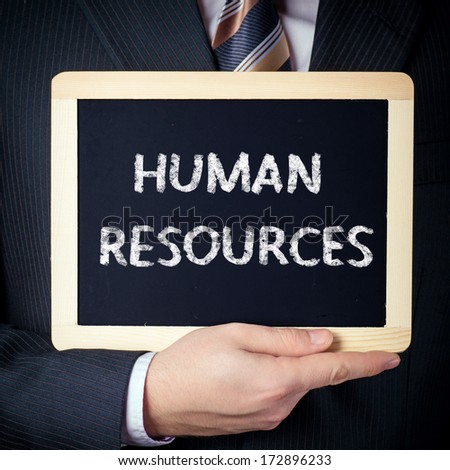 Human resources. Business man holding board on the background with business word