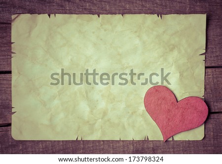 Old card on aged wood decorated with wooden heart