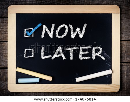 Now and Later Check Boxes on blackboard on wooden background