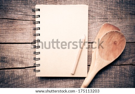 Old recipe notebook, spoons on wood background