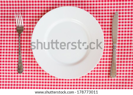 Fork Knife and Plate isolated on a red table cloth