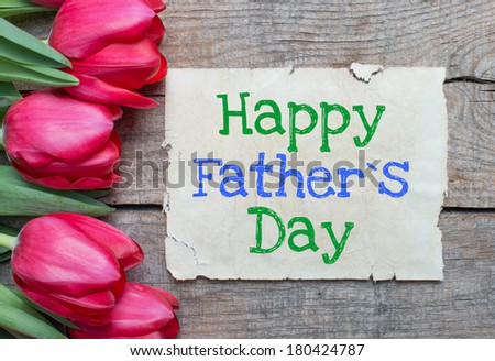 Tulips and paper with text Happy father day on wooden table