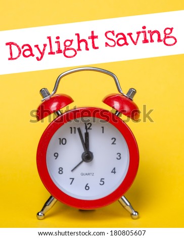 Alarm-clock on yellowand white background with text Daylight Saving