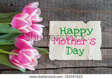 Tulips and paper with text Happy Mother`s Day on wooden table