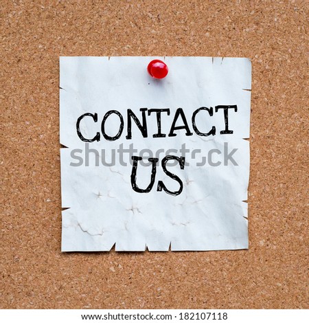 Paper note pinned to a cork notice board with the phrase Contact Us written onto it
