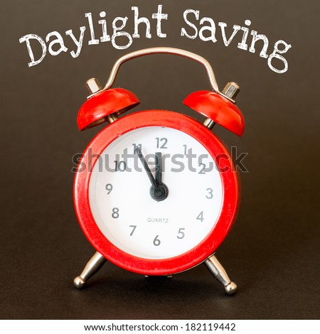 Alarm clock on brown background with text Daylight Saving