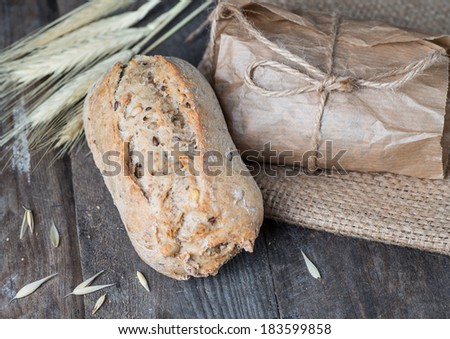 Delicious bread packed in paper on sacking on a wooden table.
