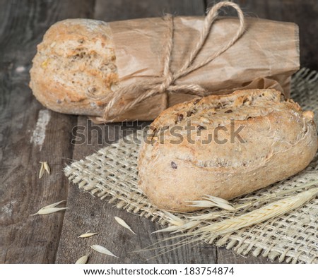 Delicious bread packed in paper on a wood table on sacking