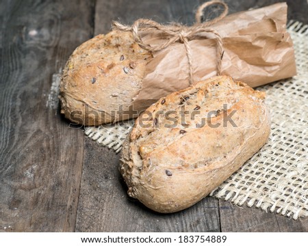 Delicious bread packed in paper on a wood table on sacking