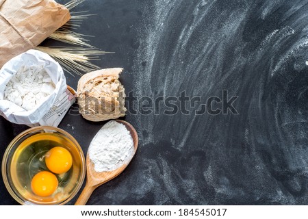Flour, eggs, and cooking utensils on a wooden cutting board.