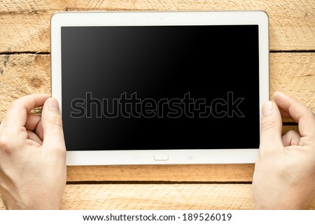Male hands holding tablet pc with green empty screen on wooden background