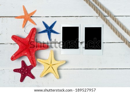 Polaroid empty photos decorated with starfishes over white wooden background