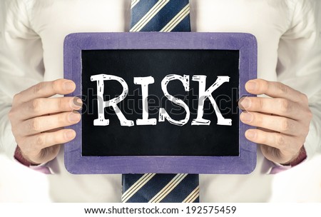Risk. Business man holding board on the background with business word