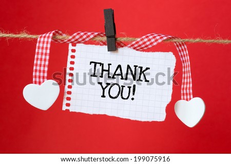 Thank You message written on a paper hanging on the clothesline on red background with two paper hearts