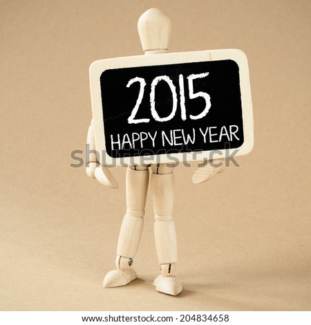 A wooden man holds a slate with message of New year 2015 celebration.