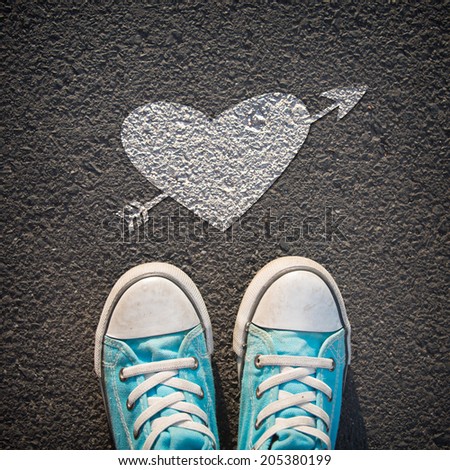 Male sneakers on the asphalt road with drawn heart