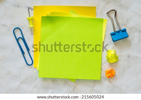 Sticky notes isolated on old paper background with clipping path pins and other office supplies . Above view.