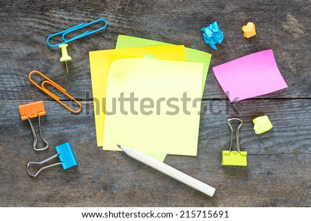 Sticky notes isolated on wooden background with clipping path pins and other office supplies . Above view