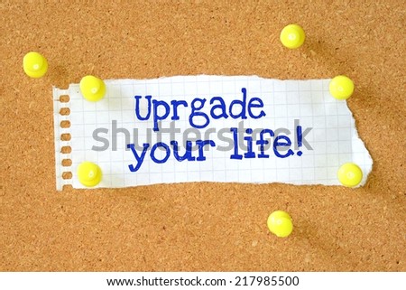The phrase Upgrade Your Life typed on a piece of paper and pinned to a cork notice board