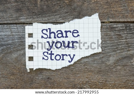 The phrase share Your Story typed on a piece of lined paper on wooden board