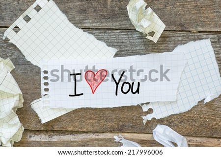 Text I love you on short note vintage paper with tape on the old wood wall background