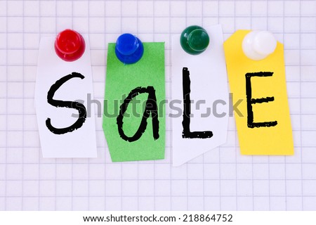 The word Sale in cut out magazine letters pinned to a paper sheet
