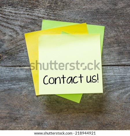 Sticky note on a wooden wall with the words Contact Us on it