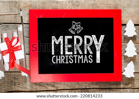 Merry Christmas. Christmas decorations with sledge and hand made candles with place for greeting on chalk blackboard. Toned photo.