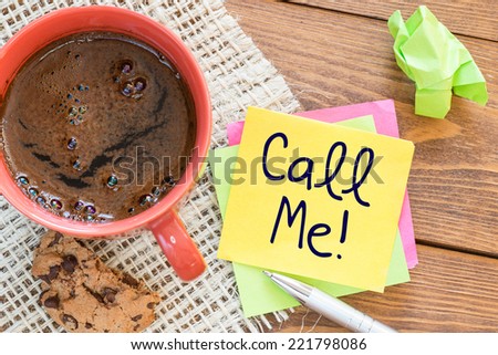 Call me noted on desk with coffee biscuit and pen,Office concept
